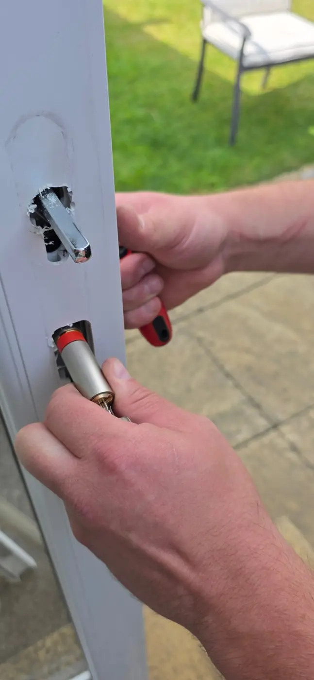 Locksmith fitting a new anti-snap cylinder into a white uPVC door in Fermanagh