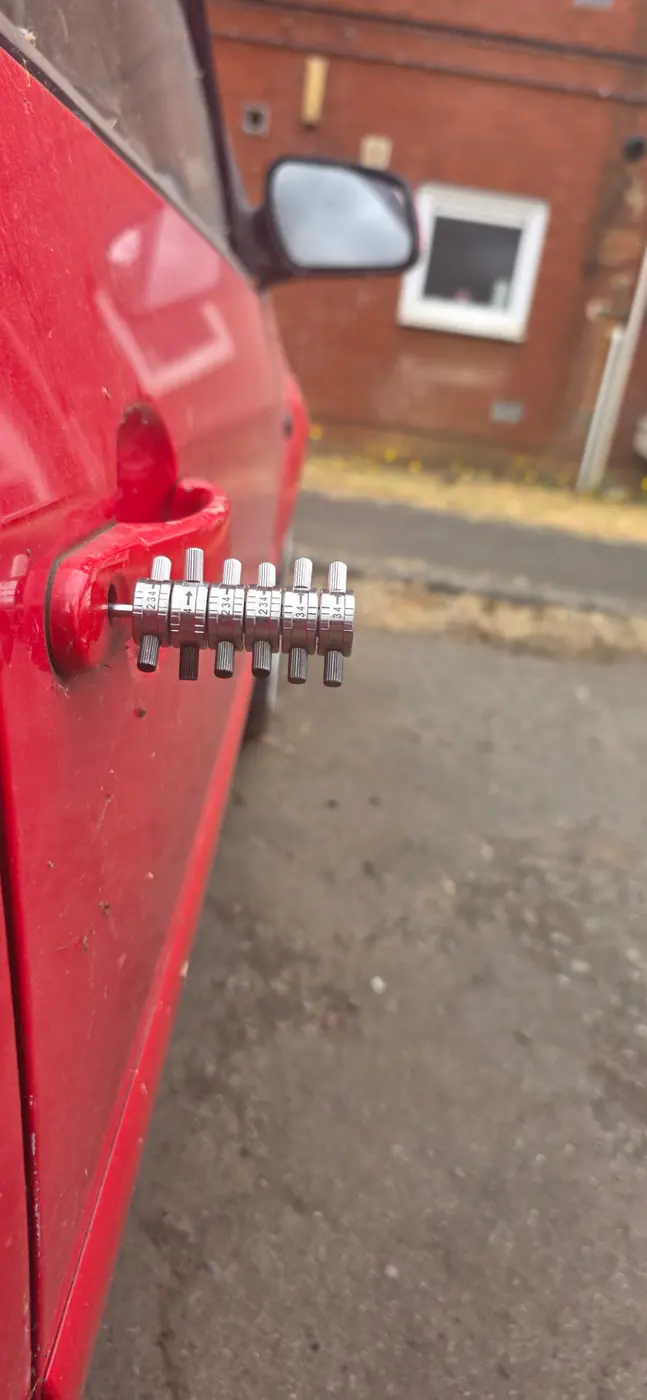 Red car door being opened with professional locksmith tools by Lost My Key NI in Fermanagh